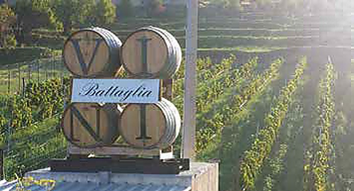 L'insegna Battaglia Vini tra i vigneti, con le botti che compongono la scritta VINI